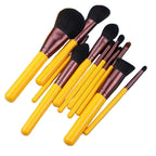Set of makeup brushes with yellow handles and brown ferrules on a light blue background