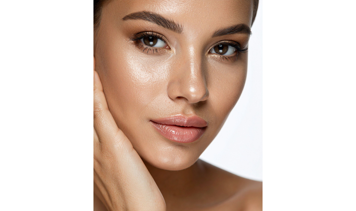 A close-up portrait of a woman with smooth, radiant skin and subtle makeup, shown against a plain white background.