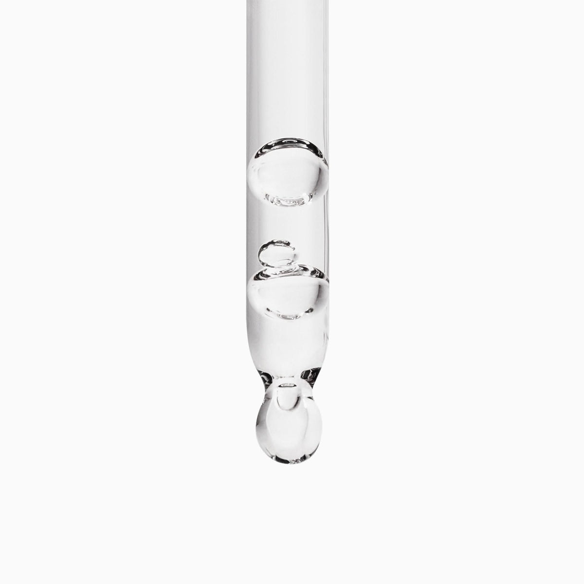 A clear glass dropper with a single large drop of transparent liquid hanging at the tip, centered on a plain white background.