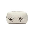 White towel with brown embroidered bows on a dark surface