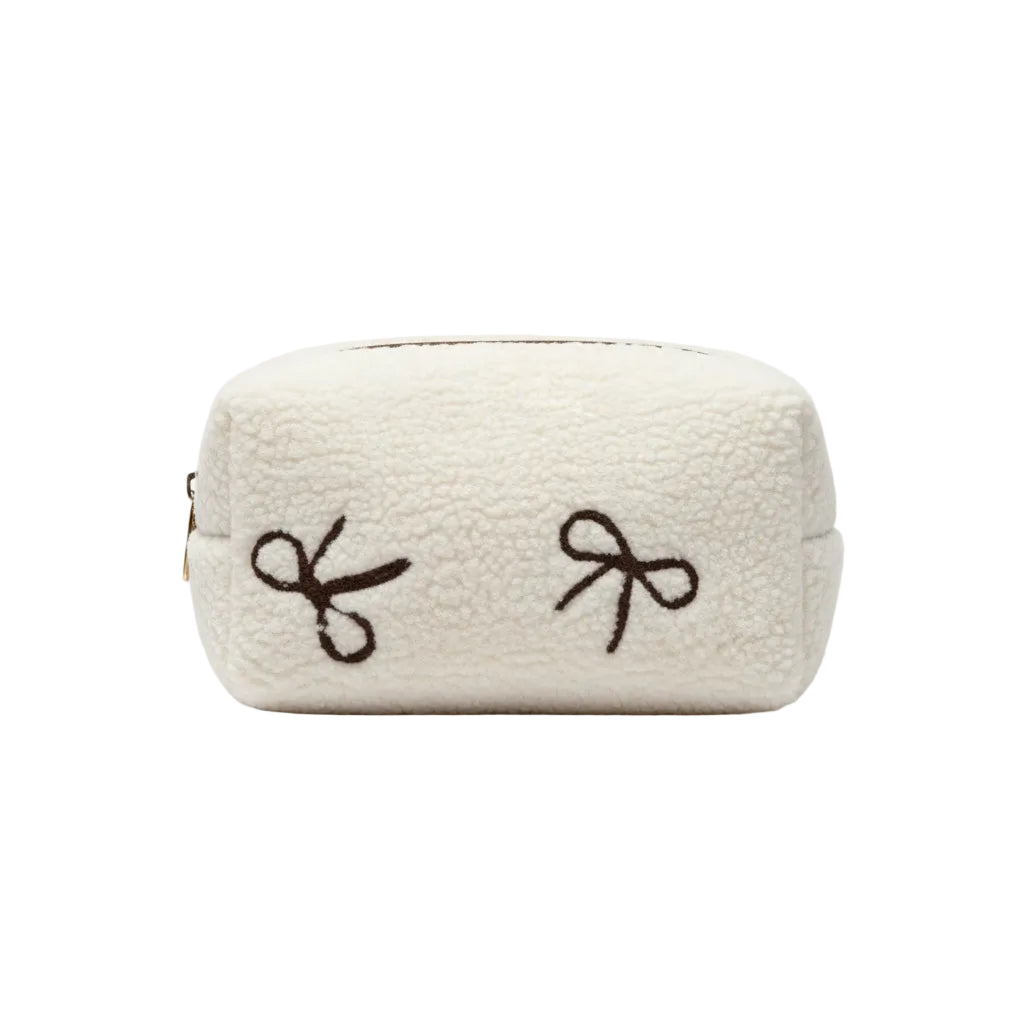 White towel with brown embroidered bows on a dark surface