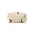 Beige pouch with embroidered designs on a dark surface