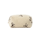 Beige pouch with embroidered designs on a dark surface
