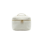 Two cream-colored textured bags with gold zippers on a dark surface.