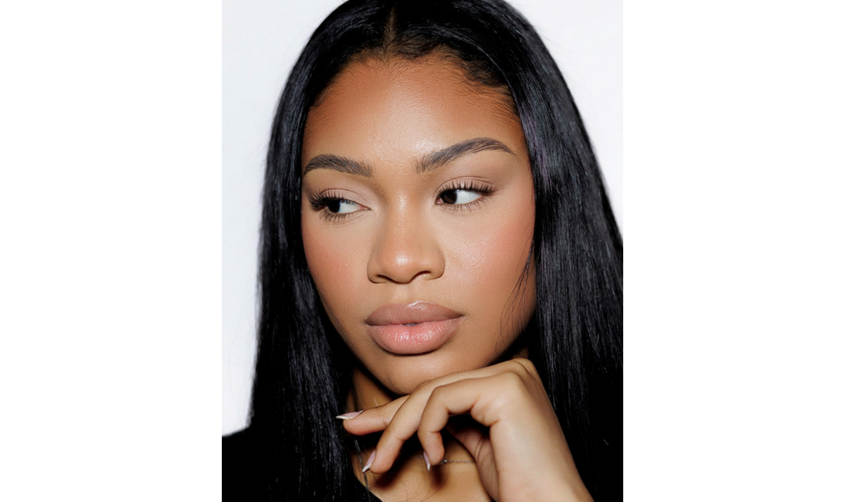A close-up portrait of a woman with long, straight black hair, wearing a black top against a plain white background.