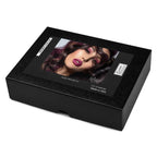 A black rectangular wig box with a glossy front label showing a model with dark purple hair and magenta lipstick, photographed on a white background.