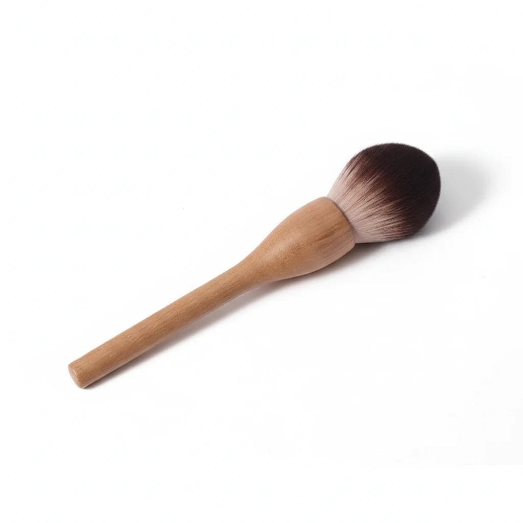 Makeup brush with wooden handle and brown bristles on a light gray background